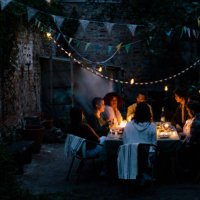 multiracial friends during dinner party in illuminated back yard - garden decoration stock pictures, royalty-free photos & images