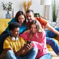 multiracial group of friends sitting in modern city apartment buying concert tickets by mobile phone. - concert stock pictures, royalty-free photos & images