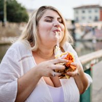 nahaufnahme einer frau, die draußen fast food isst und genießt - junk food stock-fotos und bilder