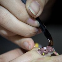 Nail artist Suzuki Ai paints a teddy bear design on a woman's fingernail at Ita Color's Yellow nail salon on February 27, 2014 in Akihabara district,...