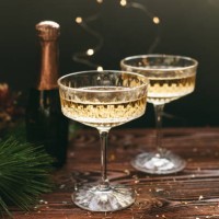 new year greeting card. champagne vintage glasses and bottle decorated with christmas decorations, pine, lights and confetti over dark wood background - home decoration stock pictures, royalty-free photos & images