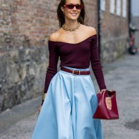 Nina Sandbech is seen wearing high waisted blue pleated skirt, burgundy off shoulder top, Gucci sunglasses, bag, necklace at Oslo Fashion Week on...