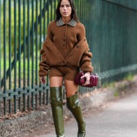 Nina Urgell Cloquell wears dark brown fuzzy long sleeve sweater, dark brown oversized jacket, shiny dark brown fuzzy mini shorts, shiny dark green...