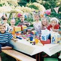 nine children sitting at a table at a birthday party - garden decoration stockfoto's en -beelden
