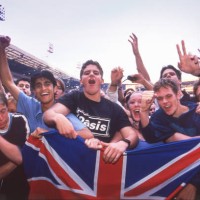Oasis fans holding a union jack flag in the audience at Wembley Stadium, London, 21st July 2000.