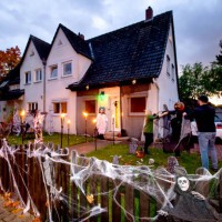October 2020, Lower Saxony, Hanover: Marleen Salewski and Julian Witte decorate a cross with artificial cobwebs in their front garden in the Bothfeld...