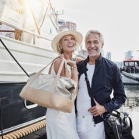 older man and young woman standing with travelling bags on jetty next to yacht - fashion stock pictures, royalty-free photos & images