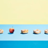 one apple in a row of donuts - junk food stock pictures, royalty-free photos & images