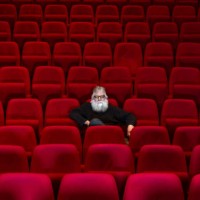 one man with white beard sits in empty cinema or theatre with comfortable red seats - concert stock pictures, royalty-free photos & images