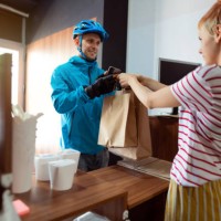 one woman, fast food worker, giving bags with prepared meals to a delivery man - junk food stock pictures, royalty-free photos & images