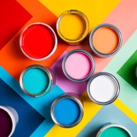 open cans with bright multicolored paints arranged on colorful geometric background divided in several parts representing concept of home repair and renovation supplies. performed in flat lay style. concept of redecoration in