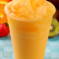 orange slush in plastic glass with fruit in the background - junk food stock pictures, royalty-free photos & images