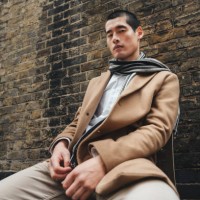 outdoor portrait of a young man on a city street sitting near brick wall, low angle shot - fashion photos et images de collection