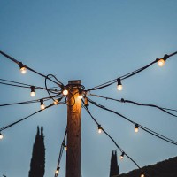 outdoor string lights illuminating wooden pole against twilight sky. - garden decoration stock pictures, royalty-free photos & images