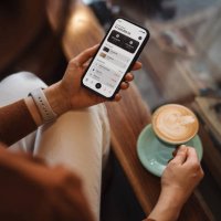 over the shoulder view of young asian woman managing personal banking and finance with online banking app on smartphone, sitting on sofa at home. financial planning. investment. wealth management, banking and finance concept.
