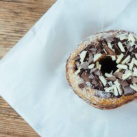 overhead view of a decadent cronut with chocolate topping on a wooden table - junk food stock pictures, royalty-free photos & images