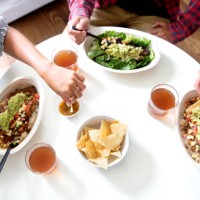 overhead view of a multi-ethnic group of millennials eating a mexican salad bowl at the kitchen table, wearing casual clothing. - junk food stock pictures, royalty-free photos & images