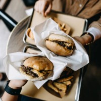 overhead view of couple sitting by the window eating burgers with french fries in a restaurant - junk food stock pictures, royalty-free photos & images