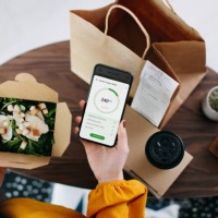 overhead view of young asian woman using health and fitness plan mobile app on smartphone to tailor make her daily diet meal plan, checking the nutrition facts and calories intake of the home delivery takeaway grilled chicken