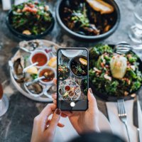 overhead view of young woman taking photos of scrumptious and delicious meal on dining table with smartphone before eating it in restaurant. eating out lifestyle. camera eats first culture - food stock pictures, royalty-free 