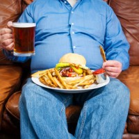 overweight man over-eating on a couch - junk food stock pictures, royalty-free photos & images