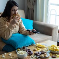 overweight woman sitting on sofa - junk food stock pictures, royalty-free photos & images