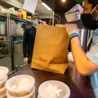 owners of local restaurant taking orders on the phone and boxing food for delivery during covid-19 pandemic - junk food stock pictures, royalty-free photos & images
