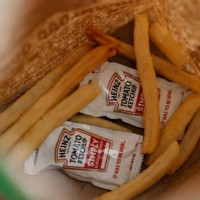Packets of Heinz ketchup sit in the bottom of a Burger King bag with french fries on April 12, 2021 in San Anselmo, California. Packets of ketchup...