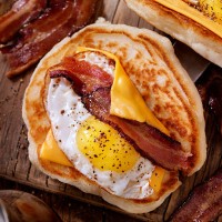 pancake breakfast taco with suny side up eggs, bacon, cheese - junk food stock pictures, royalty-free photos & images