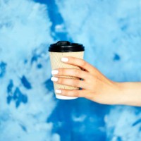 paper cup in female hands against a blue wall. - junk food stock pictures, royalty-free photos & images