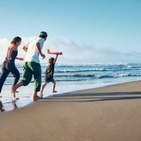 parents running behind a boy running straight ahead with a model airplane held high in one hand. - travel stock pictures, royalty-free photos & images