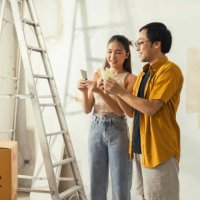 peaceful asian cheerful couple young man and woman smiling sit together on floor painting white wall with roller during renovation house relocation in new apartment happy couple painting walls - home decoration stock pictures