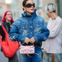 Peggy Gou wears black sunglasses, gold rings, navy blue buttoned cropped denim jean Acne Studios jacket, navy blue mid-rise washed denim jean Acne...