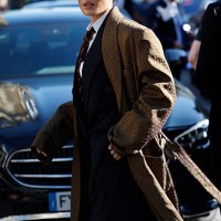 Peggy Gou wears, white shirt, burgundy striped tie, black suit, brown printed long silky coat, outside Saint Laurent, during the Menswear...