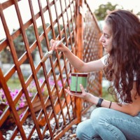peinture de clôture par une femme souriante dans l’après-midi - garden decoration photos et images de collection