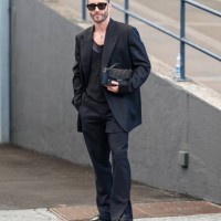 Pelayo Diaz wears black sunglasses, silver necklace, black oversized blazer jacket, black shirt, black pants, shiny black loafer moccasin leather...