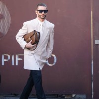 Pelayo Diaz wears sunglasses, a white shirt, a white tie, a white oversized blazer jacket, a brown leather Gucci bag, black suit pants, black leather...