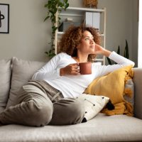 pensive multiracial woman relaxing at home, sitting on the sofa drinking morning coffee. - coffee stock pictures, royalty-free photos & images