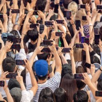 People hold up their phones while Aespa performs on ABC's 