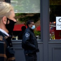 People wearing face masks wait in line in front of a restaurant open for takeout amid the coronavirus outbreak on May 11, 2020 in Alexandria,...