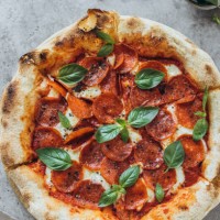 pepperoni pizza garnished with basil leaves - junk food stock pictures, royalty-free photos & images