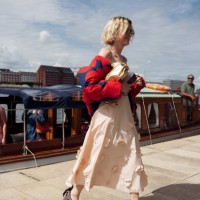 Pernille Rosenkilde wears peach or beige skirt, red and blue puffy jacket and golden bag at VIP guest trip with a boat to the Marimekko show during...