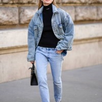 Pernille Teiba wears black sunglasses, diamonds earrings, a black turtleneck pullover from Balanciaga, a blue faded oversized jacket, blue faded...