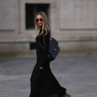 Pernille Teisbaek is seen wearing a long black dress with brown suede boots, a black Maxi leather Chanel handbag and black sunglasses during the...