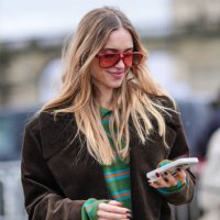 Pernille Teisbaek wears a green and pink striped top, a brown oversized jacket, sunglasses, outside Loewe, during the Womenswear Fall/Winter...