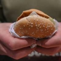 Person enjoys a burger inside a fast food restaurant, on March 28 in Krakow, Poland.