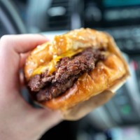 Person's hand holds a takeout burger in an automobile in Concord, California, November 25, 2022.