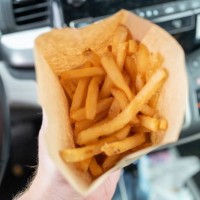 Person's hand holds a takeout french fry container in an automobile in Concord, California, November 25, 2022.