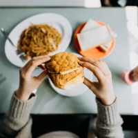 personal perspective of woman eating hong kong style local foods, sandwich, buttered pineapple bun, fried noodles and iced red bean drink in traditional restaurant - junk food stock pictures, royalty-free photos & images