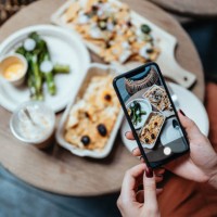 personal perspective of young woman enjoying her home delivery takeaway meal in the balcony, taking photos of delicious food with smartphone before eating it. eating in lifestyle. camera eats first culture. technology in ever